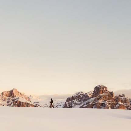 Skier traversing snowy alpine landscape at Aman Rosa Alpina resort, Italy.