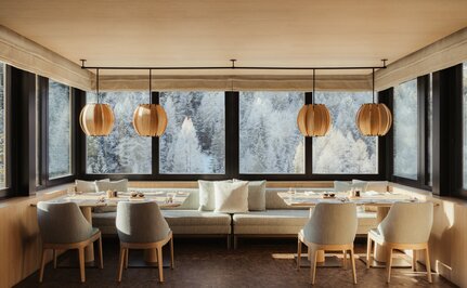 The Heritage Room at Aman Rosa Alpina resort, featuring modern artwork and elegant seating beneath tall windows.