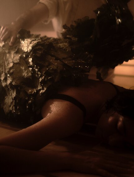 Spa therapist applying dark mineral treatment to guest's back at Amanvari's wellness facility.