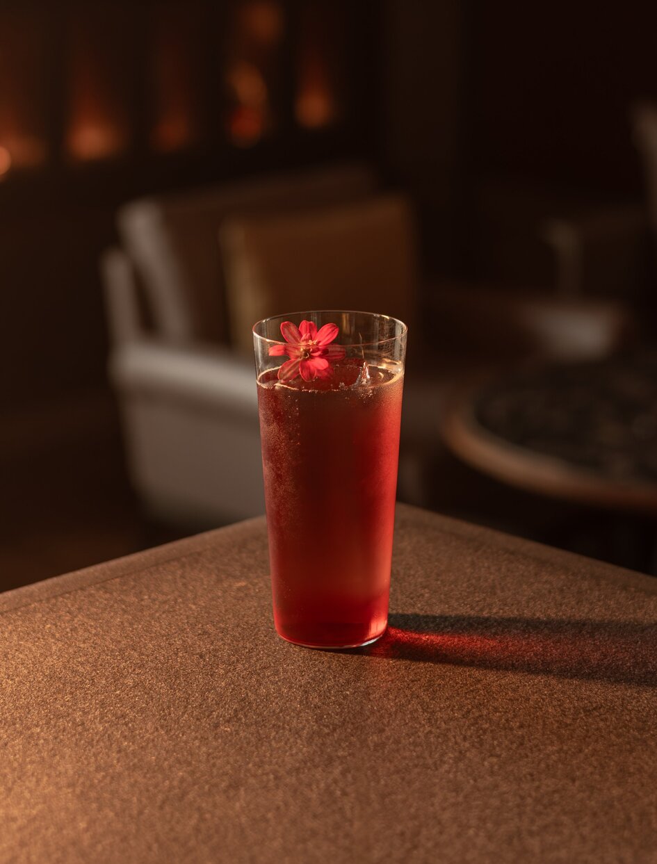 アマン ナイラート バンコクのラウンジで、赤いカクテルにフレッシュなガーニッシュを添えたグラス。