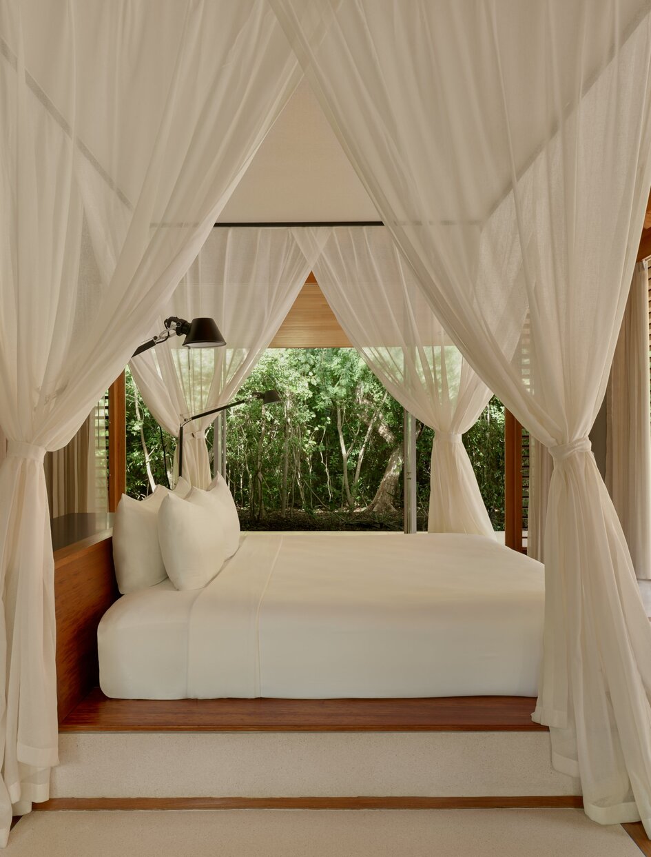 Canopied principal bedroom with sheer white curtains and potted plants at Amanyara, Turks and Caicos.