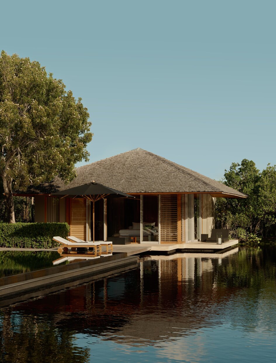 Villa with thatched roof reflected in still water at Amanyara, Turks & Caicos.