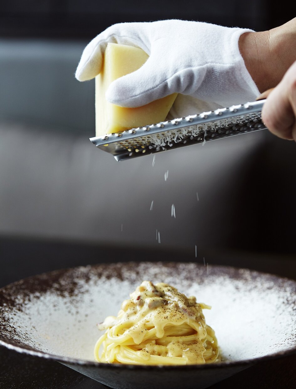 アマン東京のダイニング会場でチーズをおろす様子、パスタ・カルボナーラの仕上げ。