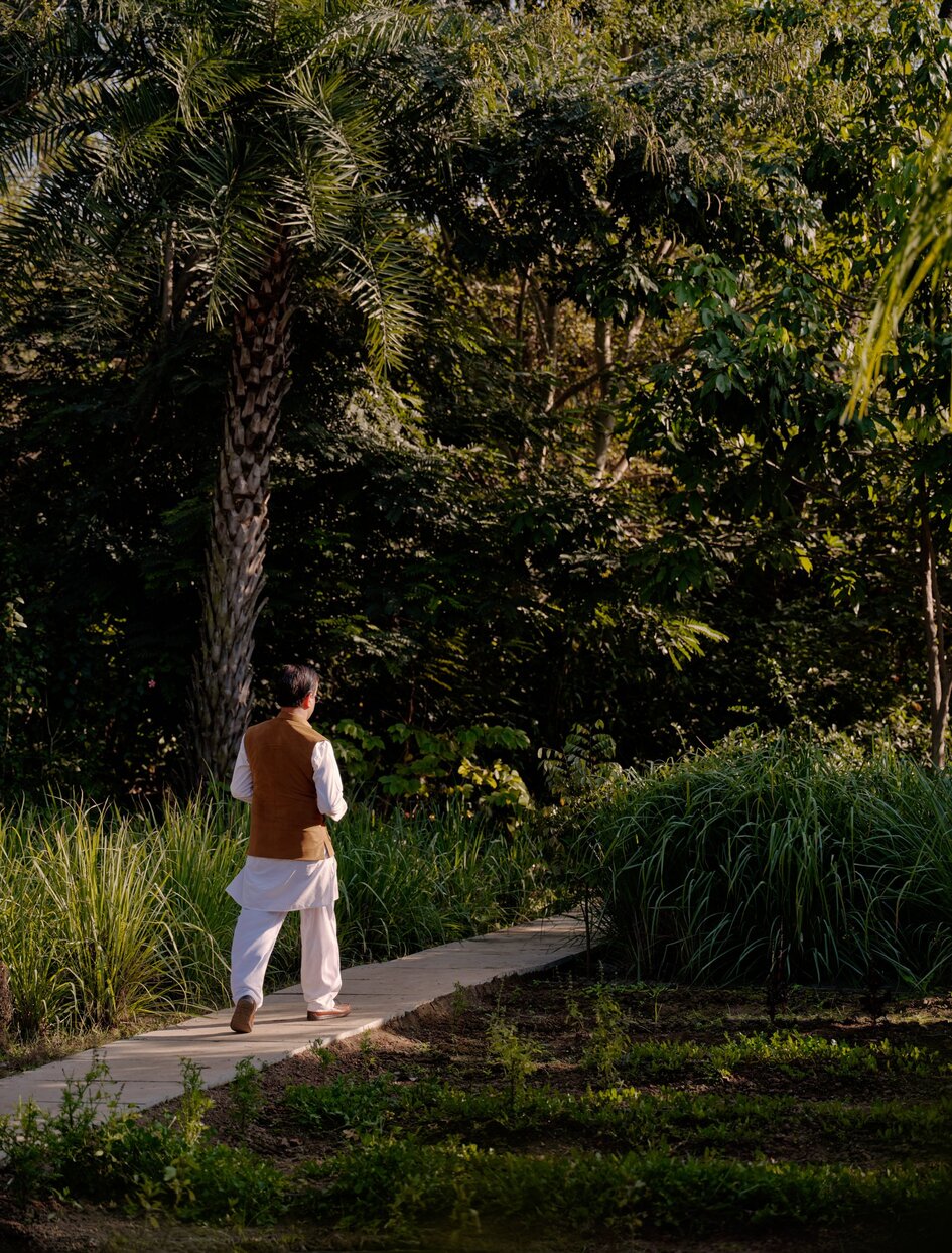 Ayurvedic doctor walking along a garden path at Amanbagh, India.