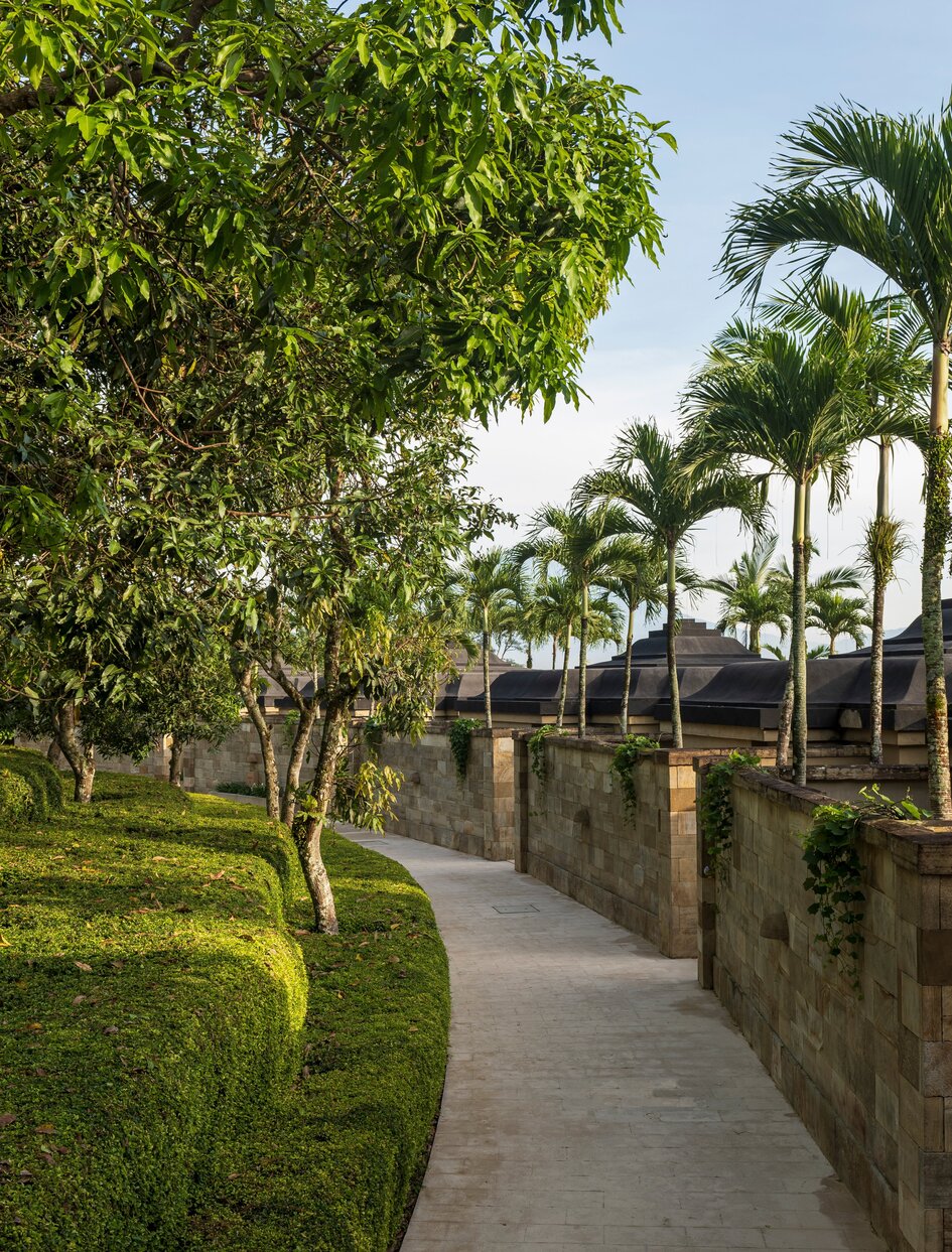 Stone pathway lined with palm trees and verdant gardens at Amanjiwo, Indonesia.