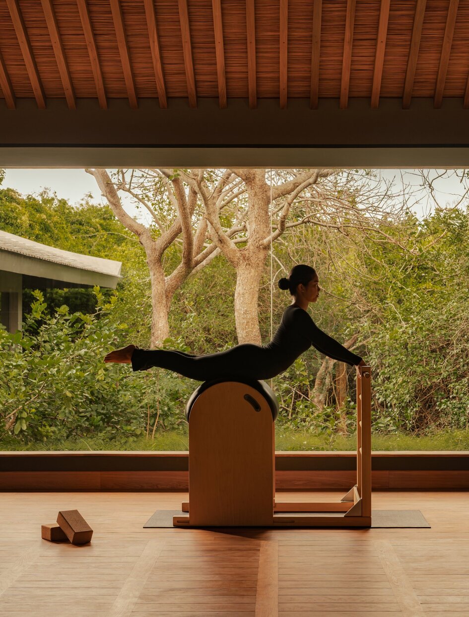 Woman practising pilates on a reformer with views of Vietnamese landscape at Amanoi.
