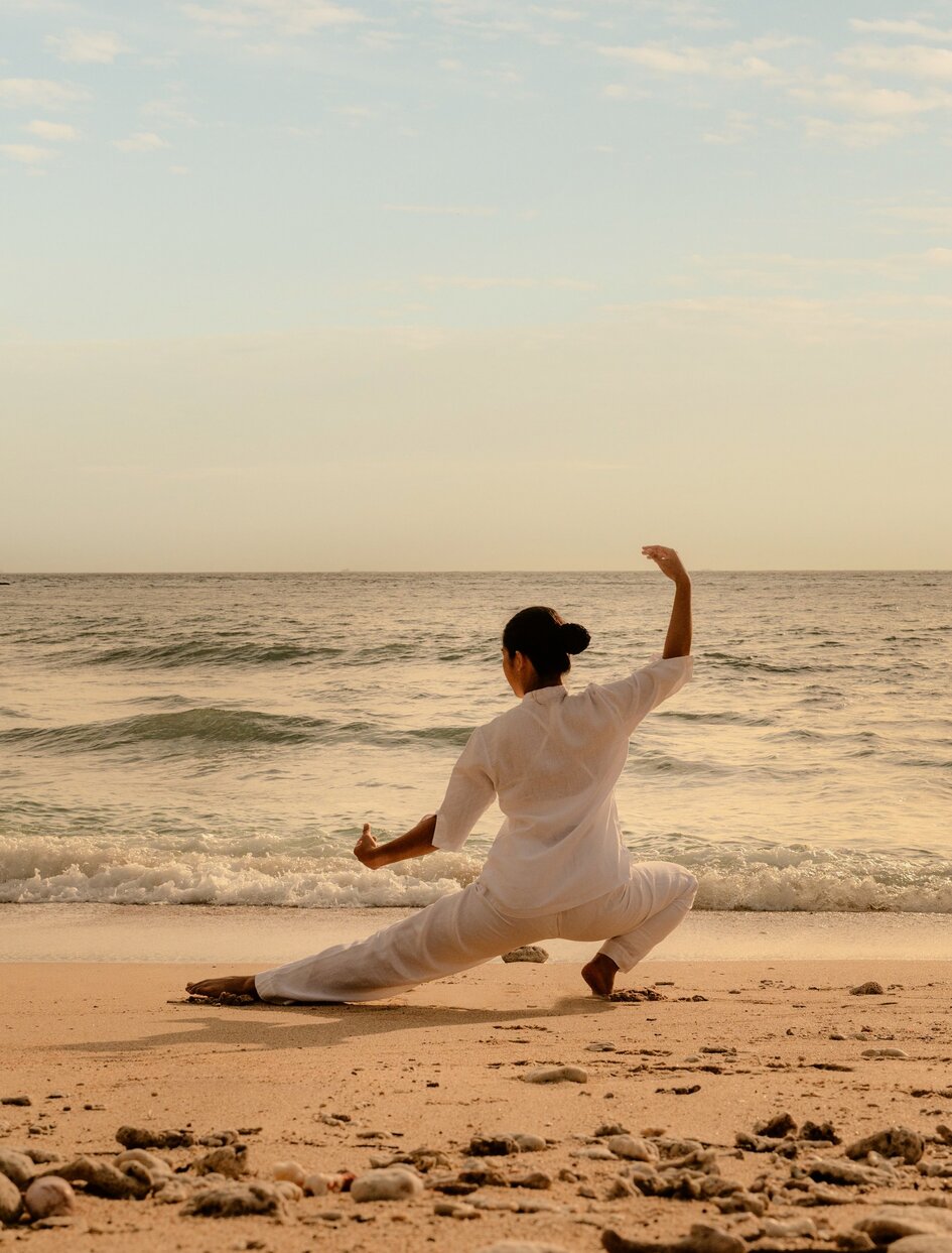 安缦诺怡度假村沙滩上，一位客人在晨曦中练习太极动作。