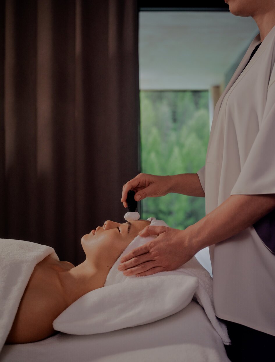 Therapist applying green treatment to guest's face during spa wellness session at Aman Rosa Alpina.