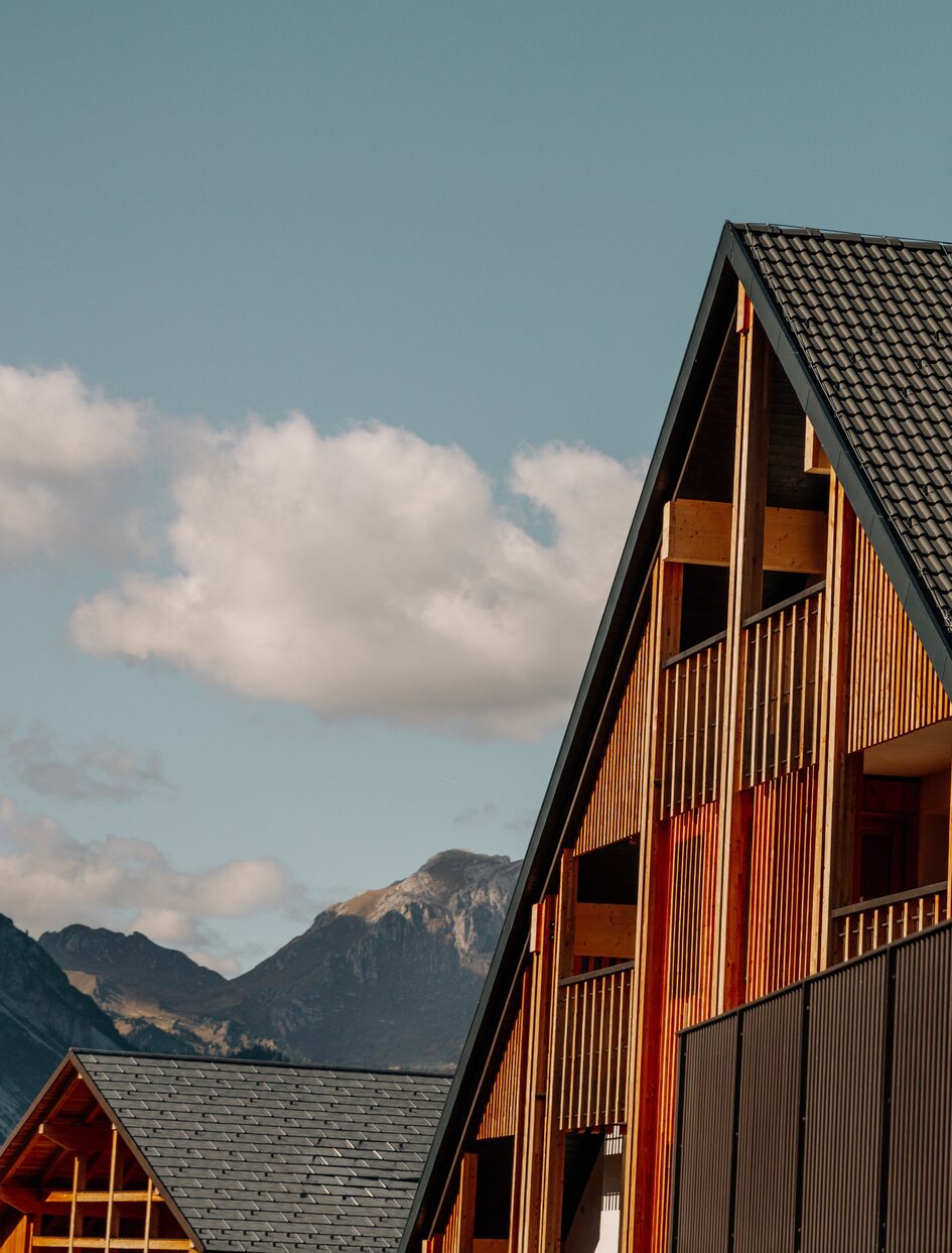 South-facing facade of Aman Rosa Alpina with pitched roof and wooden details, Italian Alps in background.