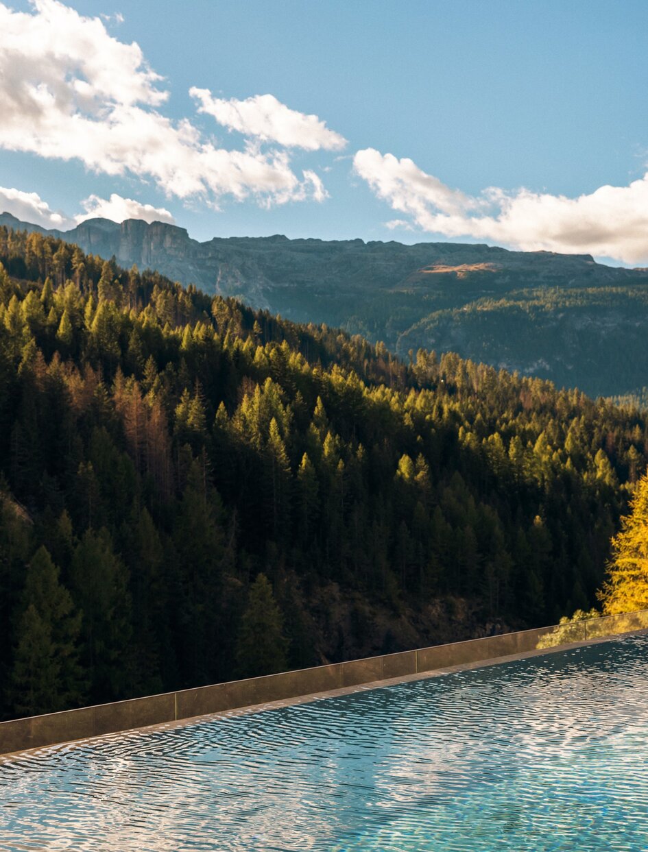 Outdoor pool at Aman Rosa Alpina overlooking forested Alpine valleys and mountains in Italy.