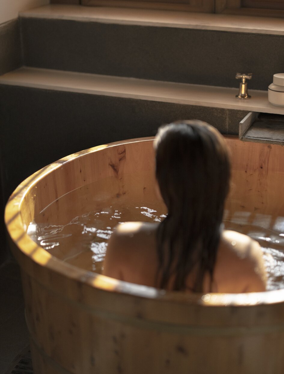 Woman's silhouette in wooden soaking tub at Amandayan spa treatment.