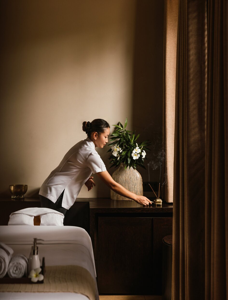 Therapist preparing a spa treatment room at Amanwella, Sri Lanka, arranging wellness amenities.