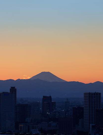 Mount Fuji silhouetted against dawn sky above Tokyo cityscape at Aman Tokyo hotel.
