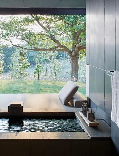Woman practising yoga by a window overlooking trees and water at Amanemu.
