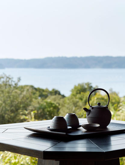 Théière et tasses sur table noire surplombant la baie, Amanemu resort.