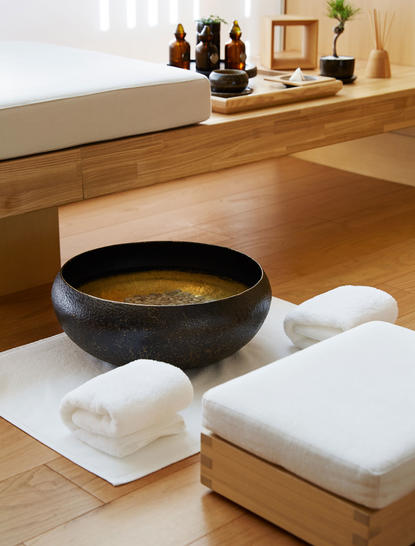 Wellness ritual at Aman Niseko featuring a black ceramic bowl with golden water and white folded towels.