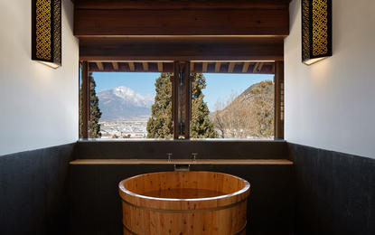 Wooden soaking tub overlooking mountain landscape at Amandayan wellness retreat.