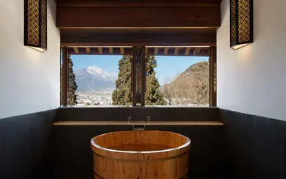 Wooden soaking tub overlooking mountain landscape at Amandayan wellness retreat.
