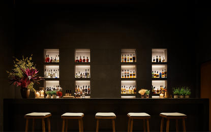Amanyangyun dining venue with illuminated bar shelving and table seating at night.