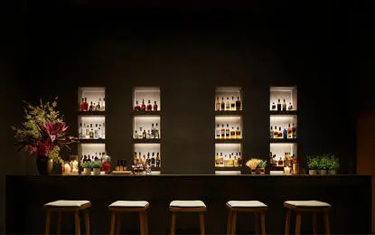 Amanyangyun dining venue with illuminated bar shelving and table seating at night.