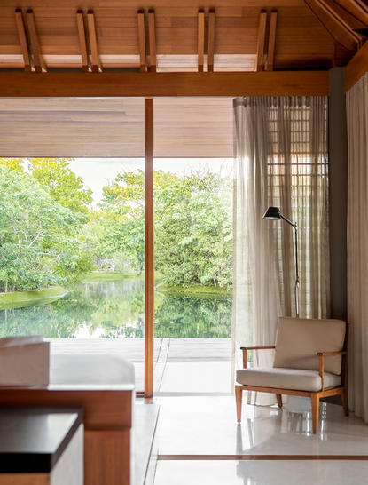 Wooden-framed glass doors opening onto a lush garden at Amanyara, with natural light flooding a calm interior space.