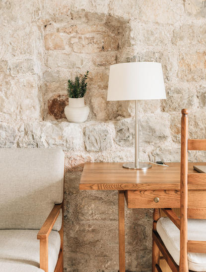 Three-bedroom village cottage at Aman Sveti Stefan with stone walls, wooden desk, and table lamp.