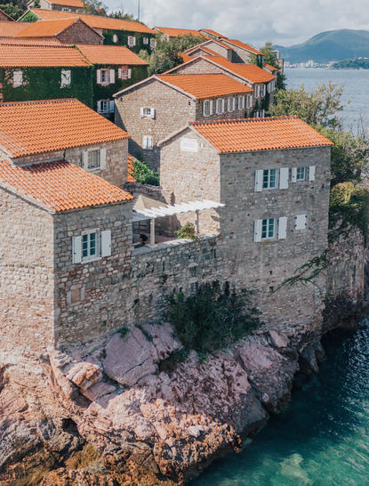 Three-bedroom village cottage at Aman Sveti Stefan perched on rocky coastline overlooking turquoise waters.