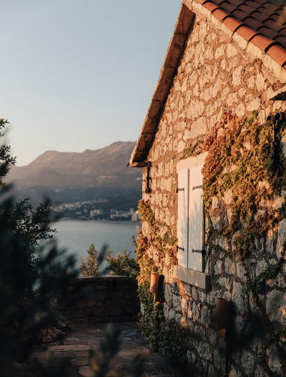 Stone cottage at Aman Sveti Stefan with views towards the Adriatic Sea at golden hour.