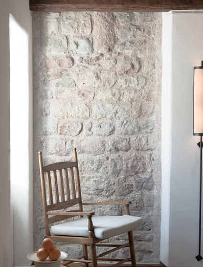 Wooden chair positioned against a textured stone wall at Aman Sveti Stefan.