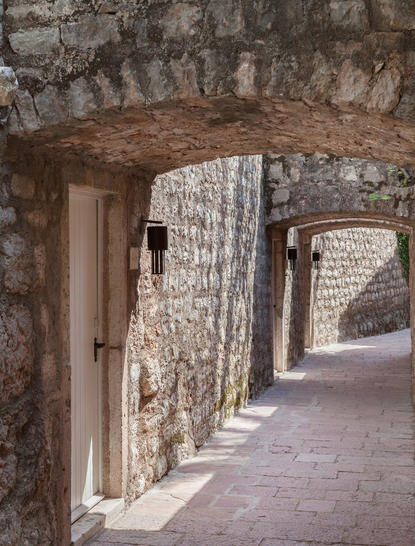 Stone archway and corridor at Aman Sveti Stefan, with weathered walls and natural light filtering through.