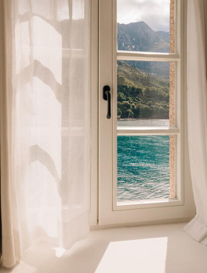 Window in Sveti Stefan Suite overlooking Adriatic Sea and coastal landscape.