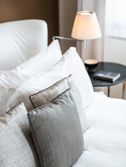 Principale camera da letto con letto matrimoniale, cuscini bianchi e lampada da comodino presso Aman Venice.