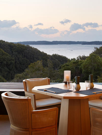 Dining area at Amanemu resort overlooking a bay and forested coastline.