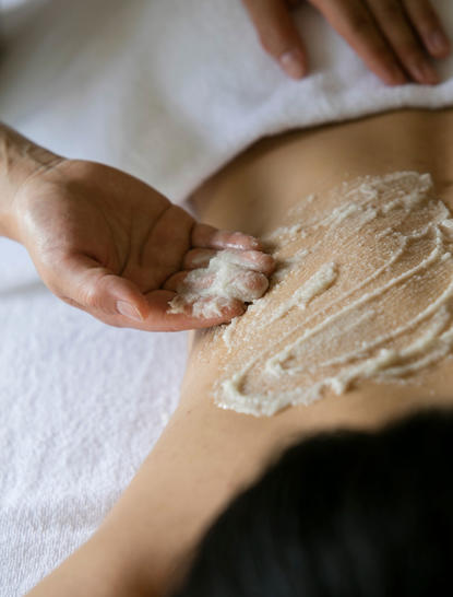 アマネムのウェルネス施設で、セラピストが客の背中に泥パックを施術している。