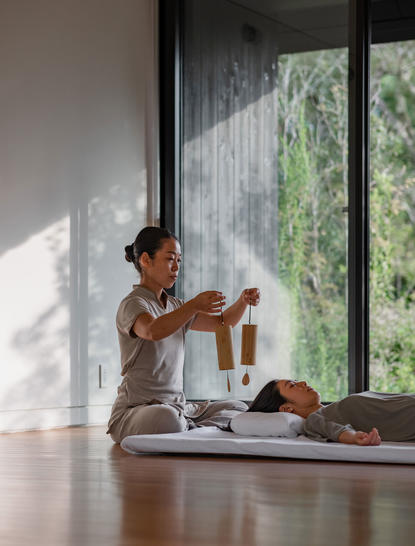 Woman seated on a sunlit windowsill at Amanemu, practising mindfulness with a book.