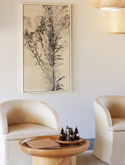 Wellness space at Amanemu with curved cream chair, wooden side table, and botanical wall art.