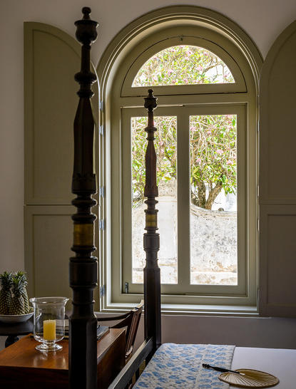 Arched doorway at Amangalla with tall wooden posts flanking glass doors, opening onto verdant grounds.