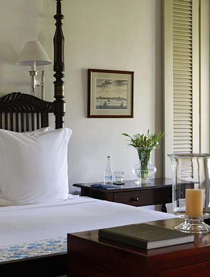 Verandah Chamber at Amangalla with four-poster bed, antique furnishings and colonial architecture.