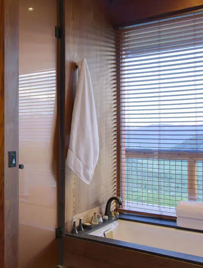 Amangani suite bathroom with slatted window overlooking mountain landscape, towel rail and sink.