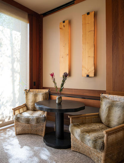 Amangani Suite seating area with two upholstered chairs, wooden wall panels, and natural light from large window.
