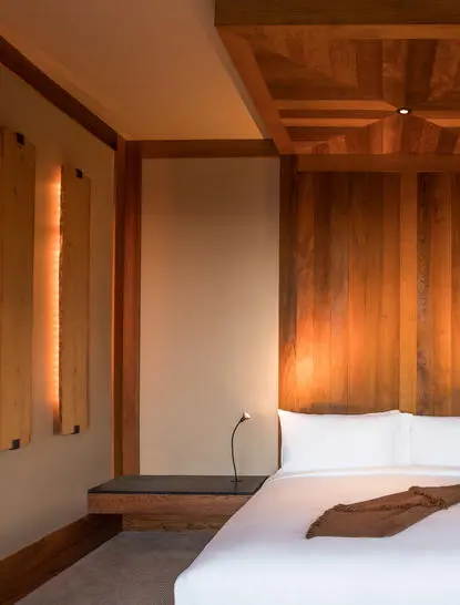 Deluxe Suite at Amangani with wooden panelling, warm lighting, and crisp white bedding.