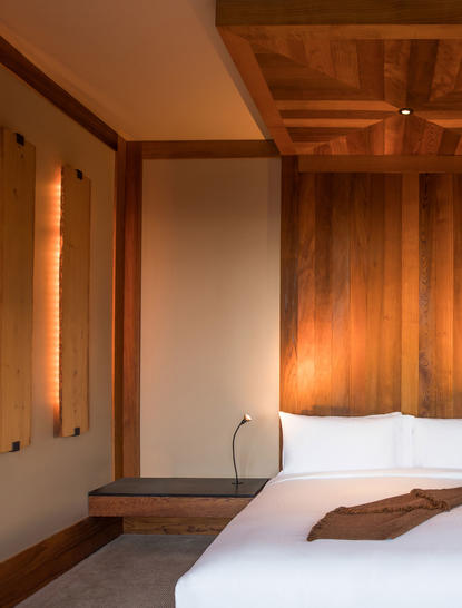 Principal bedroom in the Shoshone Suite at Amangani, featuring warm wood panelling and soft lighting.