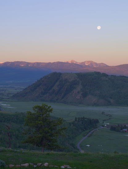 Dawn breaks over the Teton Valley viewed from Amangani, with mountains silhouetted against a pale sky.