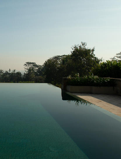 Amanjiwo's Dalem Jiwo Suite plunge pool overlooking tropical gardens at dusk.