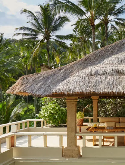 Garden Suite at Amankila with thatched-roof pavilion overlooking tropical grounds and palm trees.