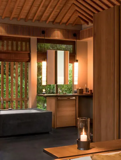 Tiled bathtub and wooden vanity in a Mountain Pavilion bathroom at Amanoi resort, with warm lighting and natural materials.