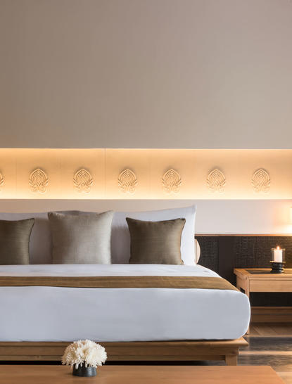 Mountain Pool Villa bedroom with bed, cushions, and wooden bedside table at Amanoi.