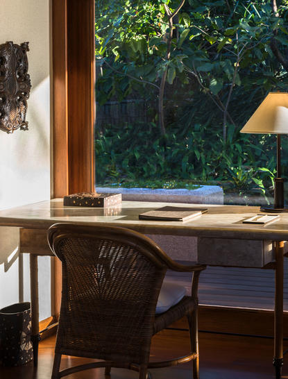 Deluxe hillside casita workspace with wooden desk, chair and warm lamp overlooking tropical gardens at Amanpulo.