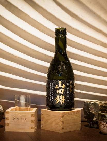 Amanpulo dining venue with an elegant bottle display and wooden boxes against a striped architectural backdrop.