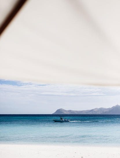 Outrigger boat on turquoise waters at Amanpulo resort.